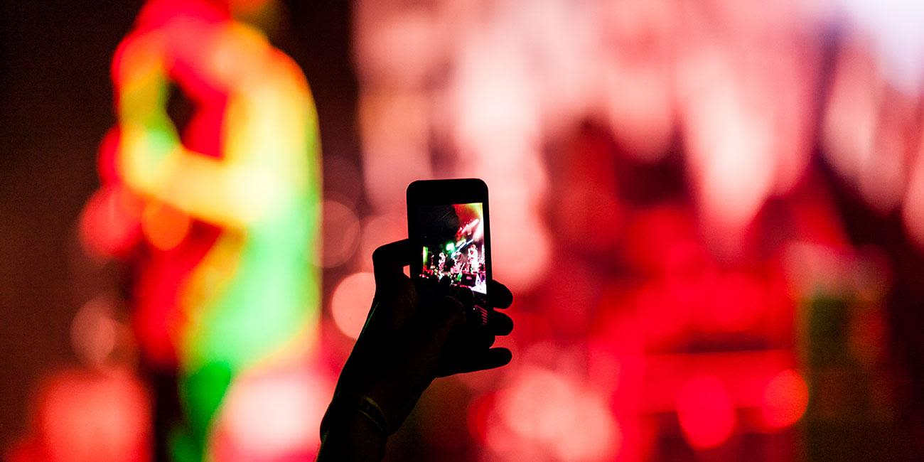 A smartphone screen showing someone filming a band playing live.