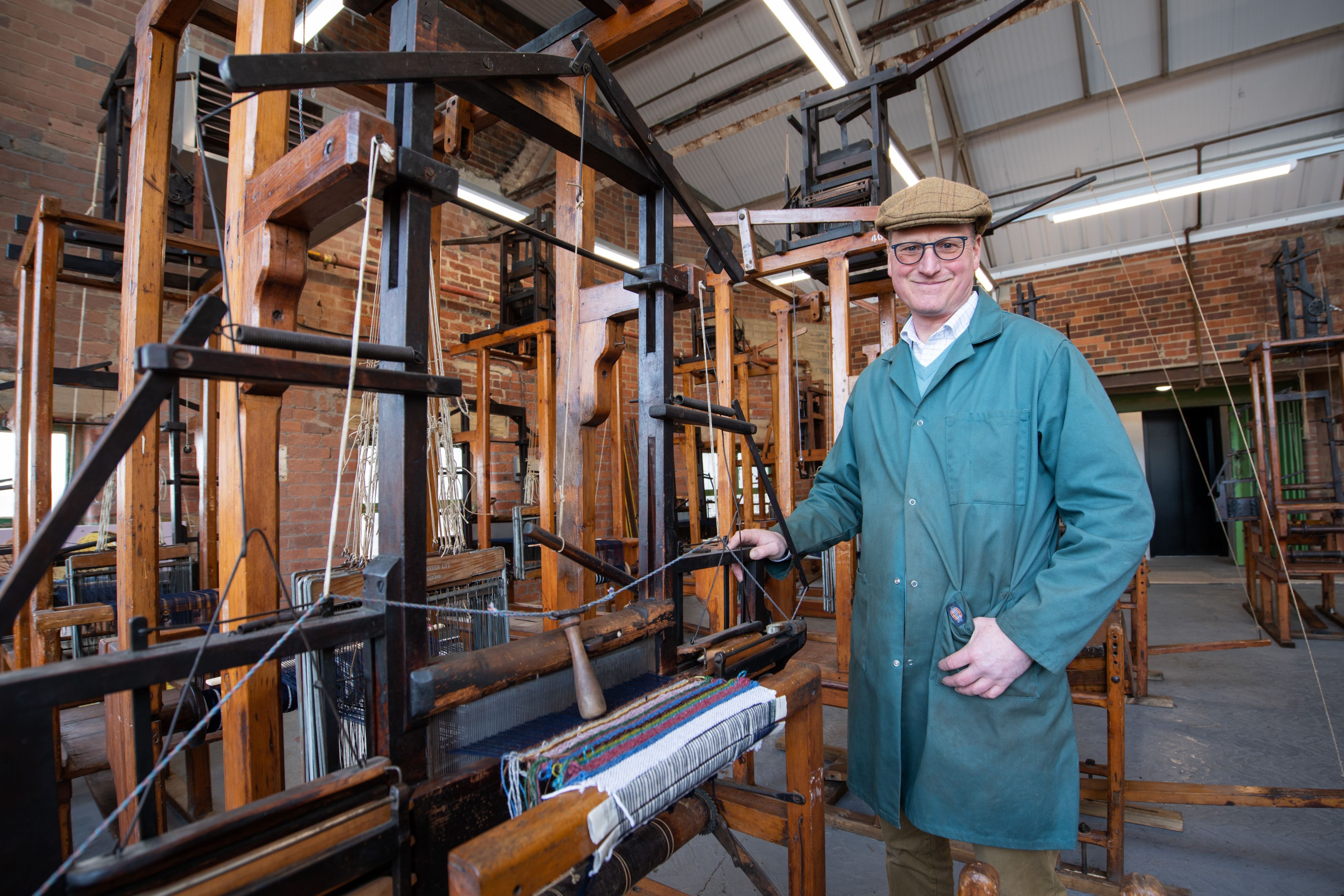 William Gaunt stands beside an old weaving loom