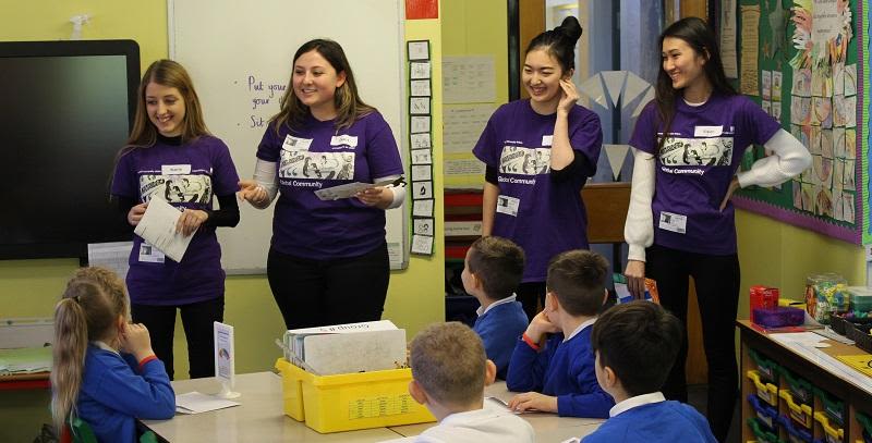 Four students from the University delivering intercultural activities to a primary school group.