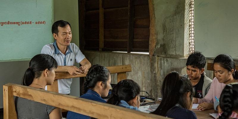 Children and a teacher in a classroom in Cambodia.