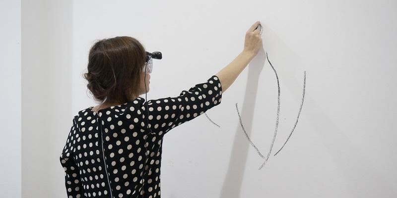 Artist Anna Ridler drawing with crayon on a wall.