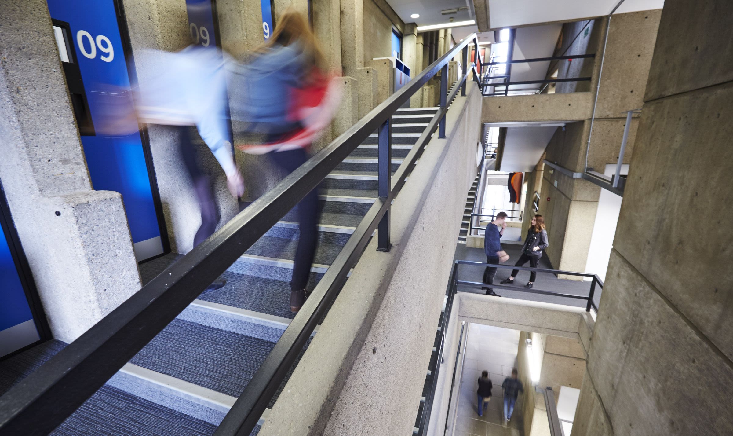 Students on a series of stairways inside a concrete building