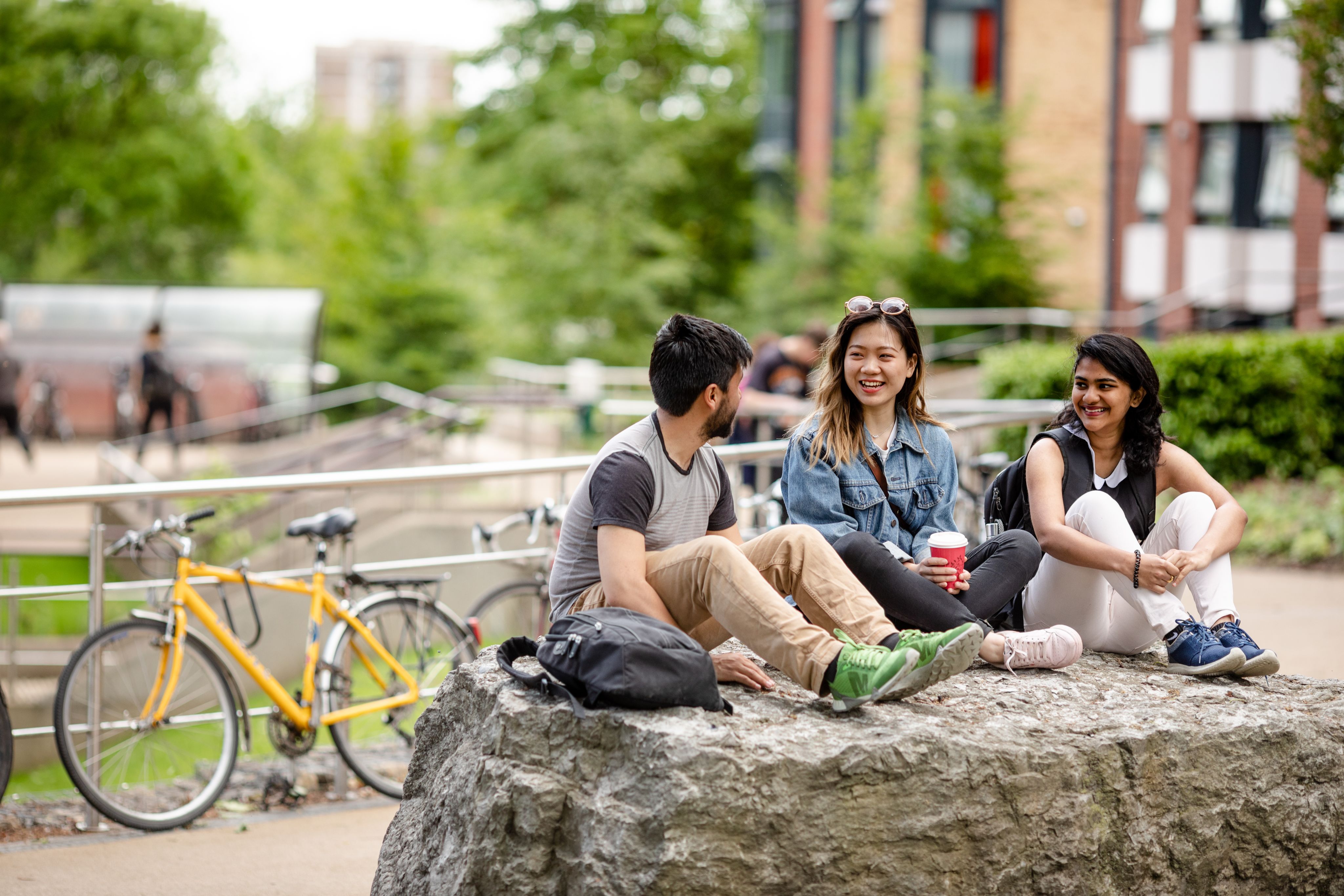 Three students sit and chat on campus