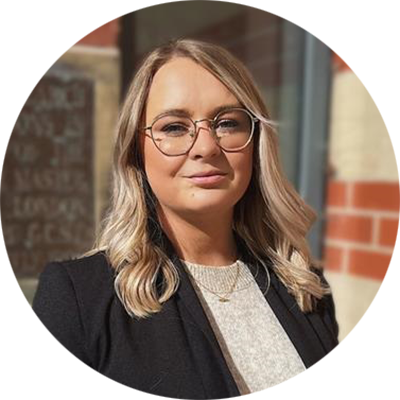 Headshot of Charlotte. She has blonde hair and is wearing glasses.