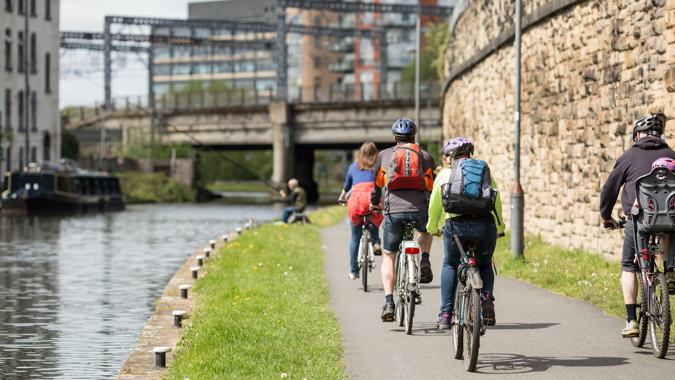 A group of adults and children cycling on the towpath next to the canal