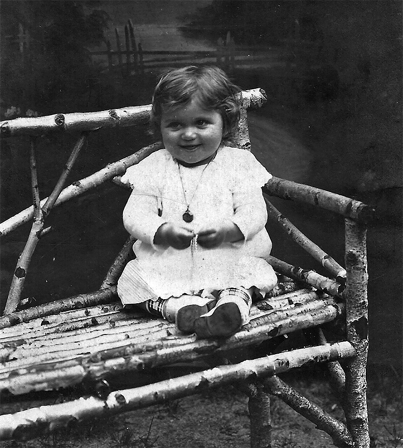 A smiling baby girl sat on a bench.