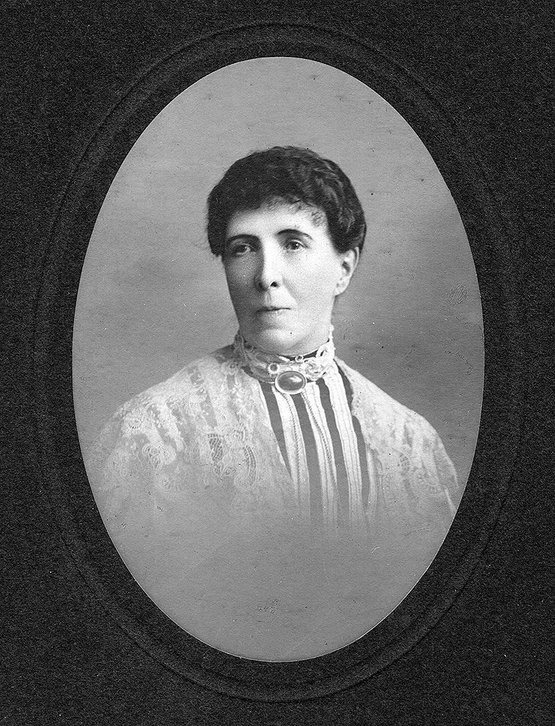An archive portrait of a woman in a high-necked blouse. She is smiling slightly and has short dark hair.