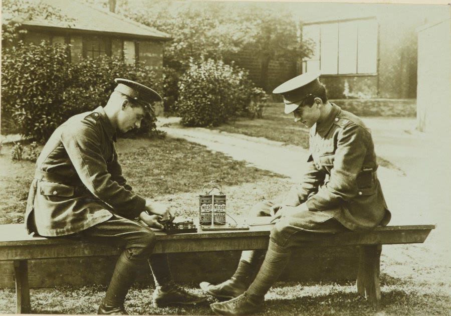 Black and white photo of two men in military uniforms facing each other on a bench