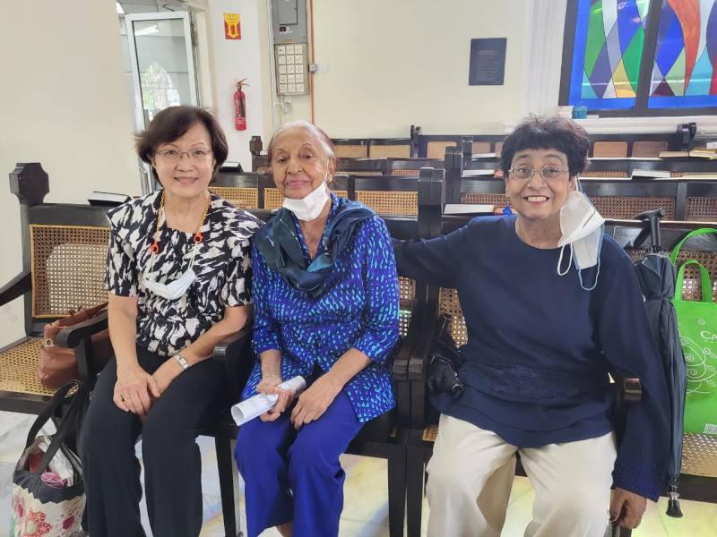 Three women sit together smiling at camera