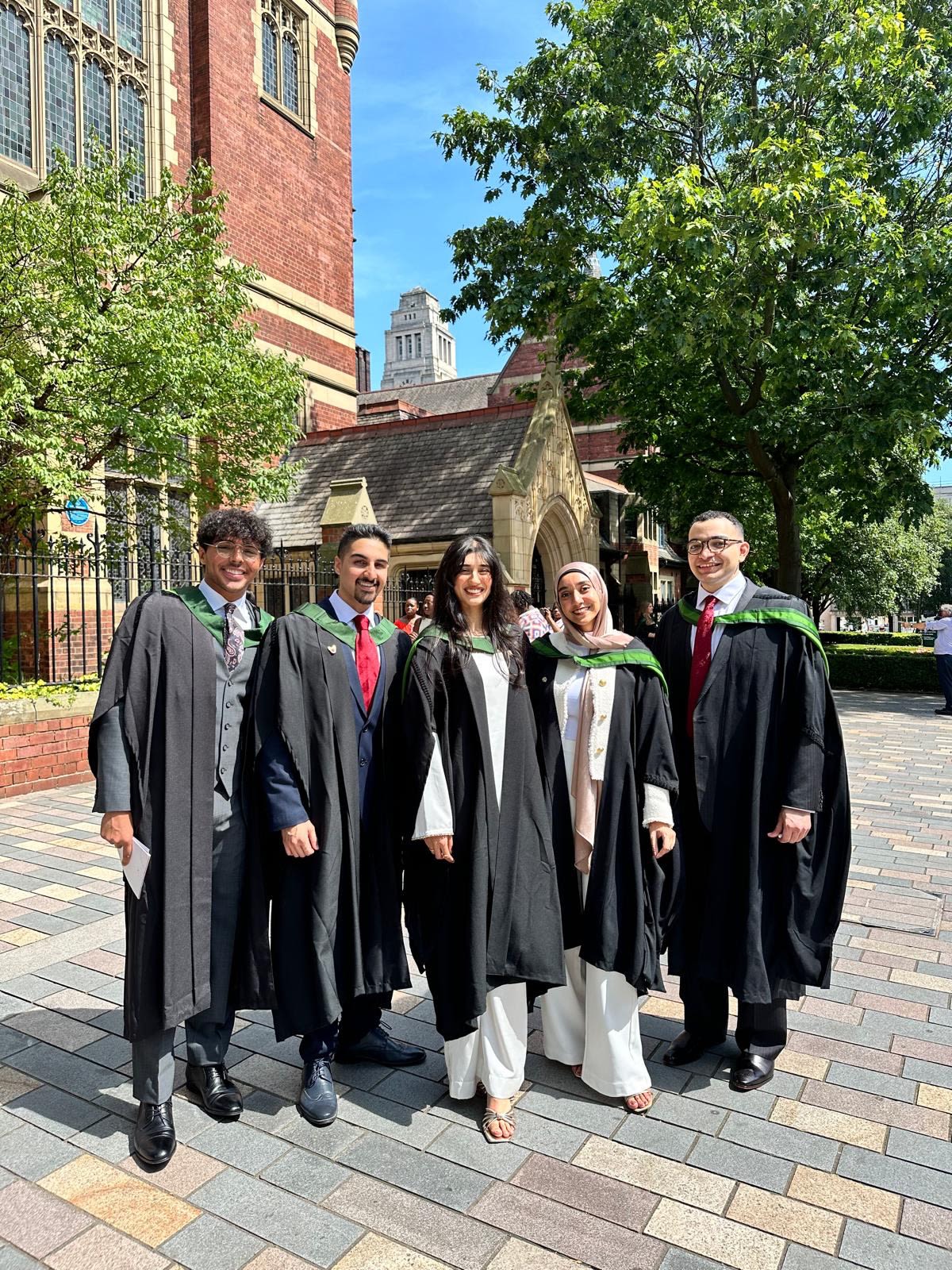 A group of graduates stand together outside the Great Hall at the University of Leeds
