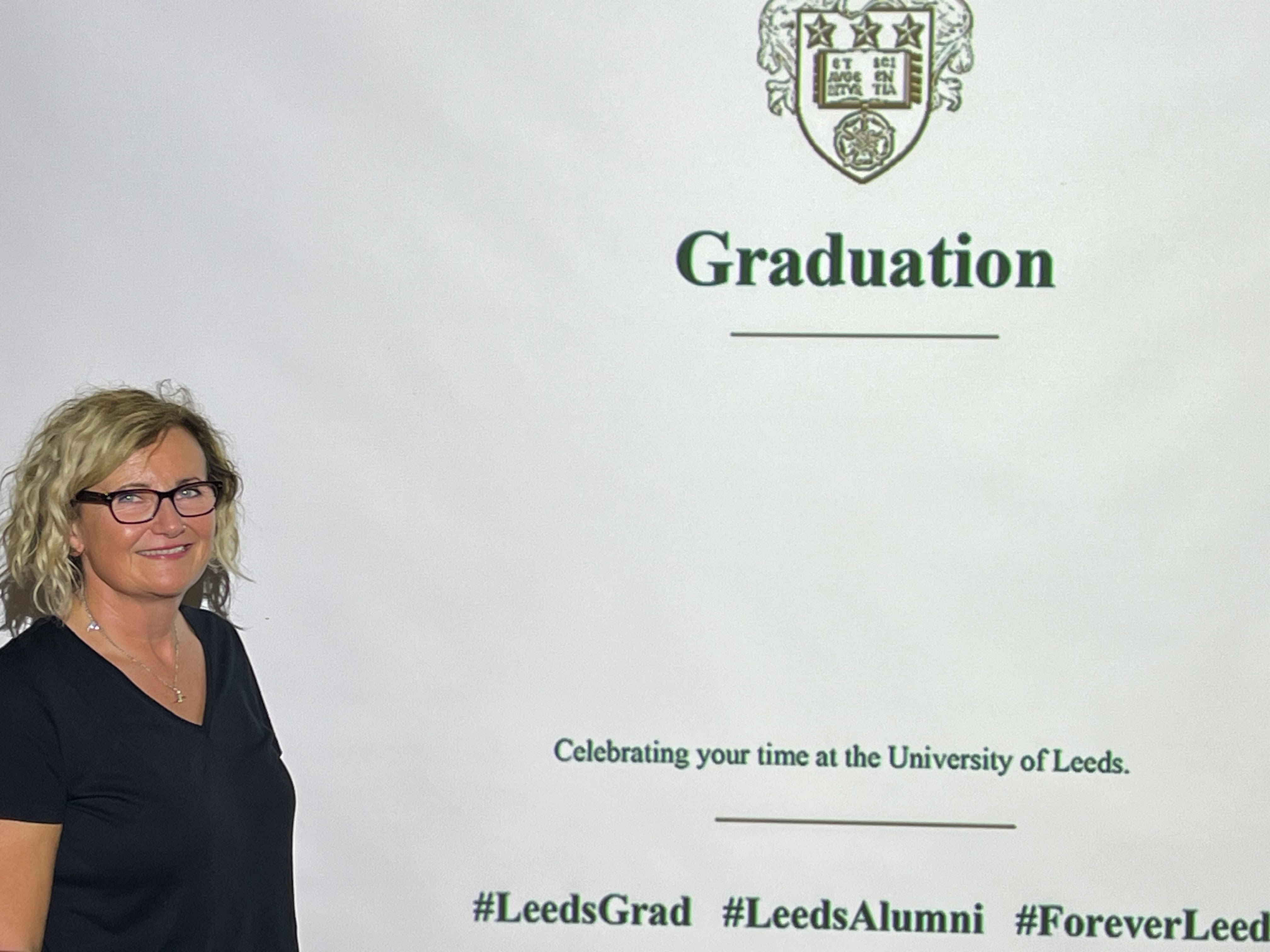 Clare Parslow stands in front of a graduation display at the University of Leeds