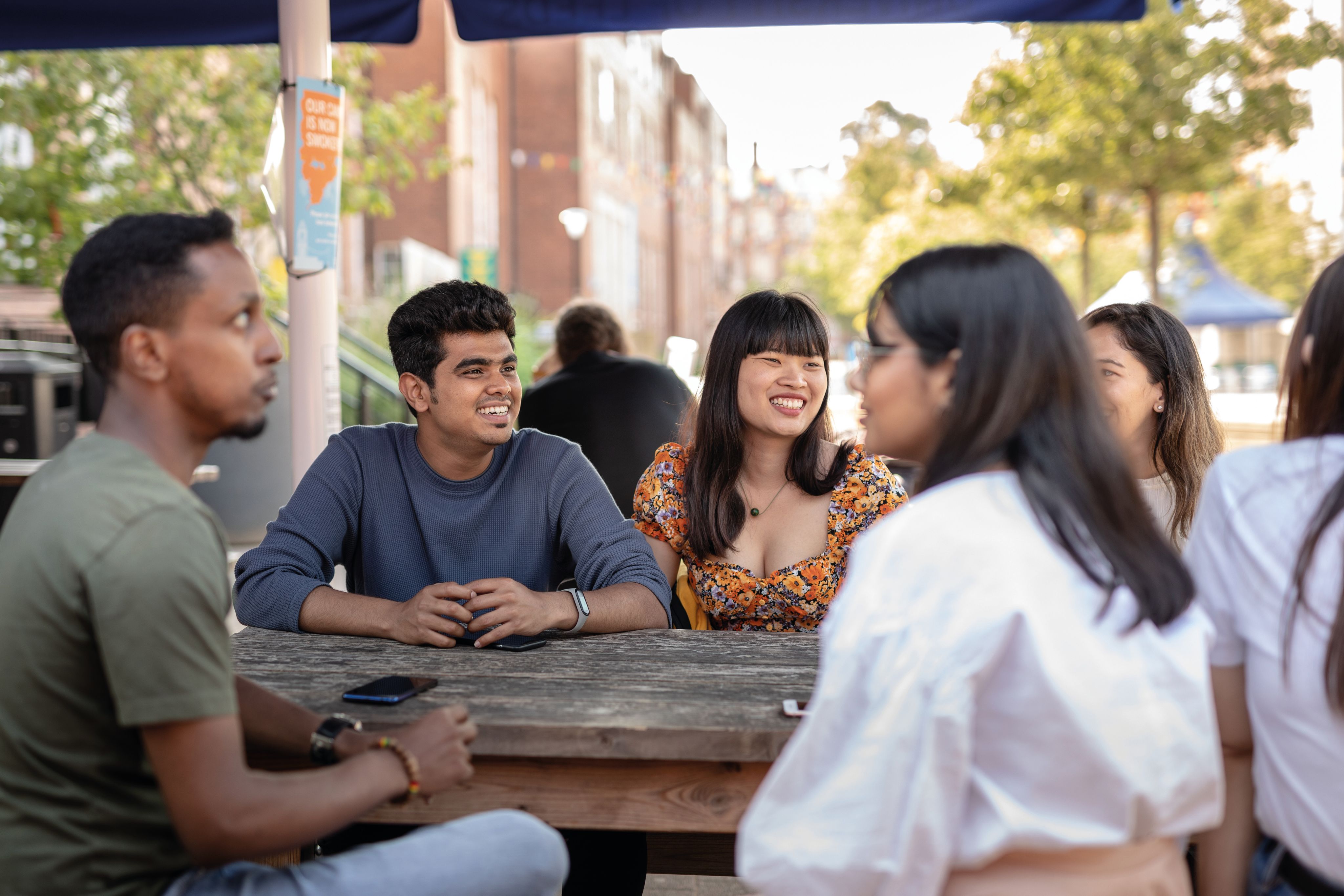 Students sat outside union on picnic table 