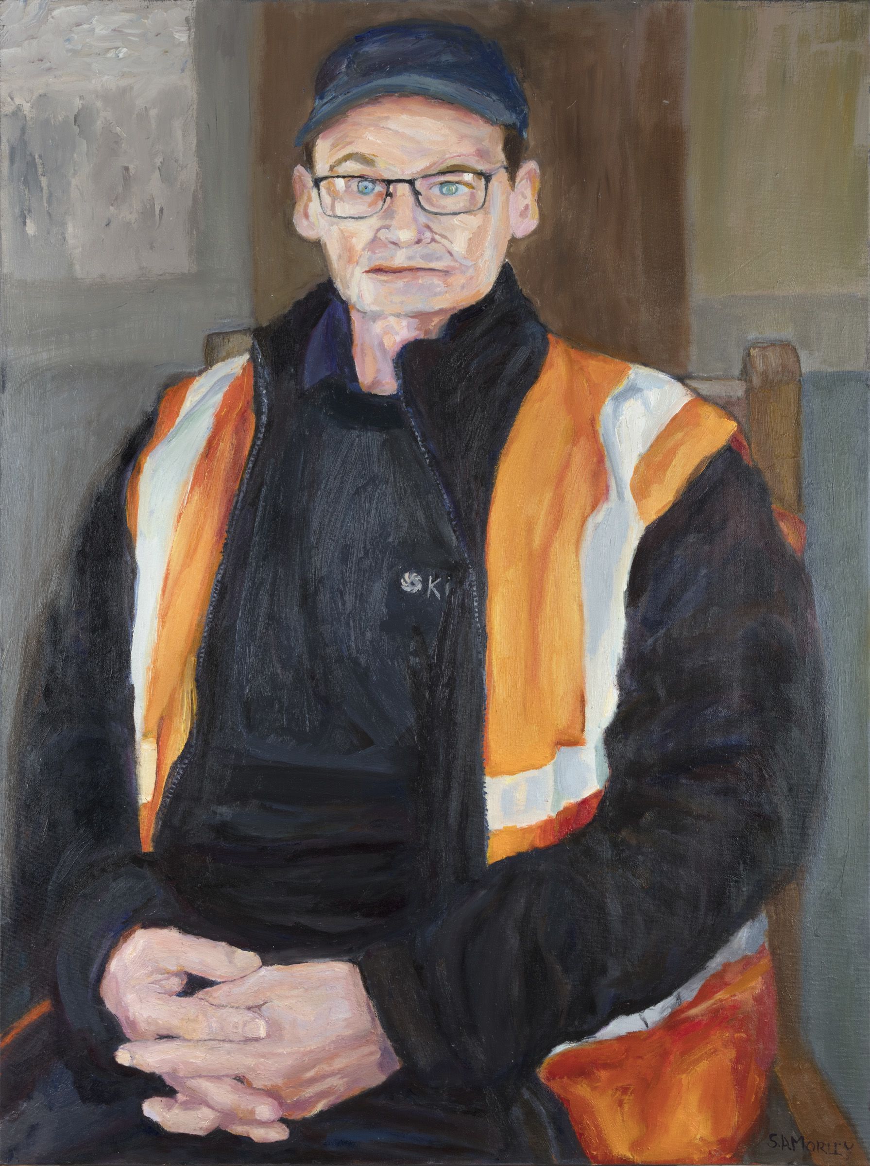 Portrait of Chris wearing a cap and his high-vis PPE at work.