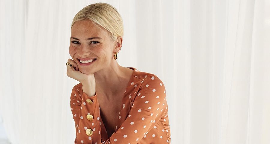 Pandora Sykes smiles for a professional photo, with her head rested on her chin.