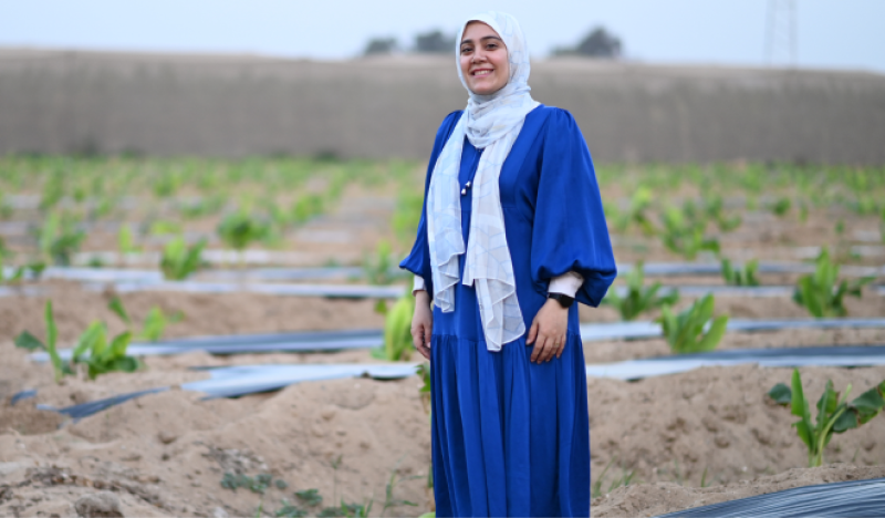 Aya Al-Sharqawy smiling for the camera in a field of crops