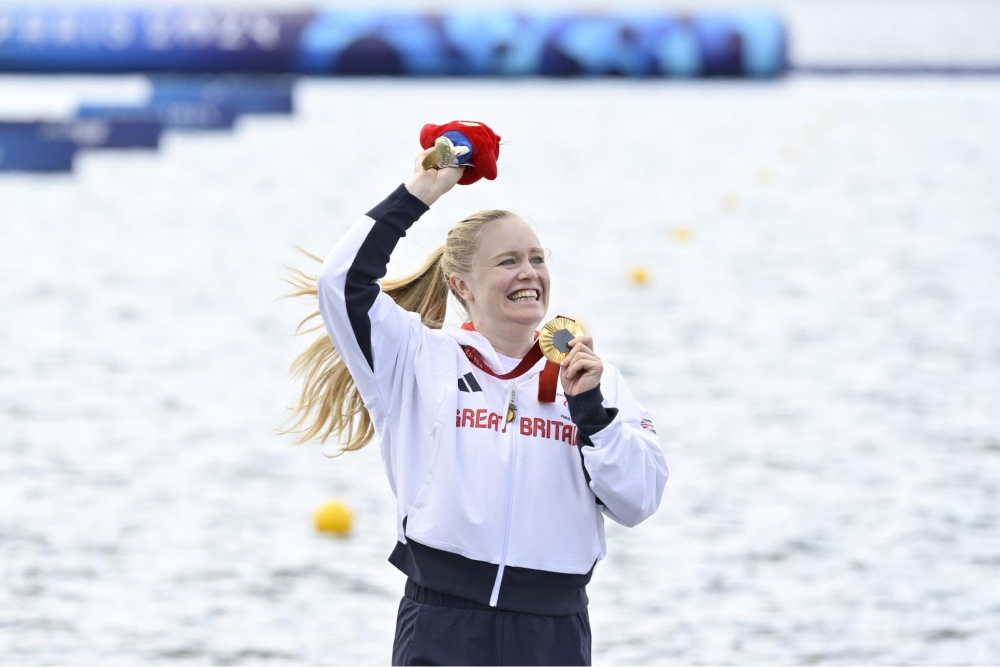 Laura Sugar stands on a podium with her gold medal