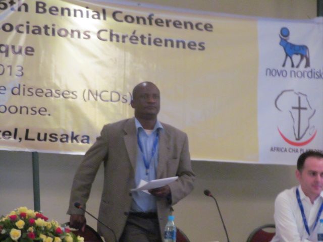 man speaking at a conference with microphone in front of him