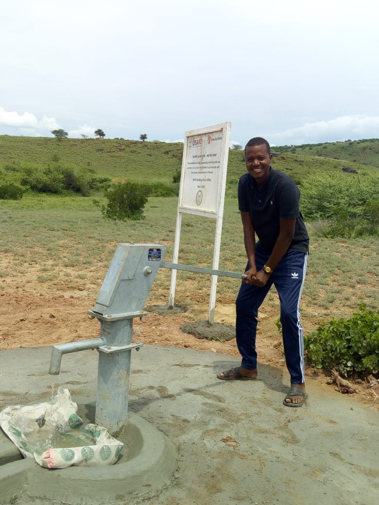 man standing at a water pump in Africa