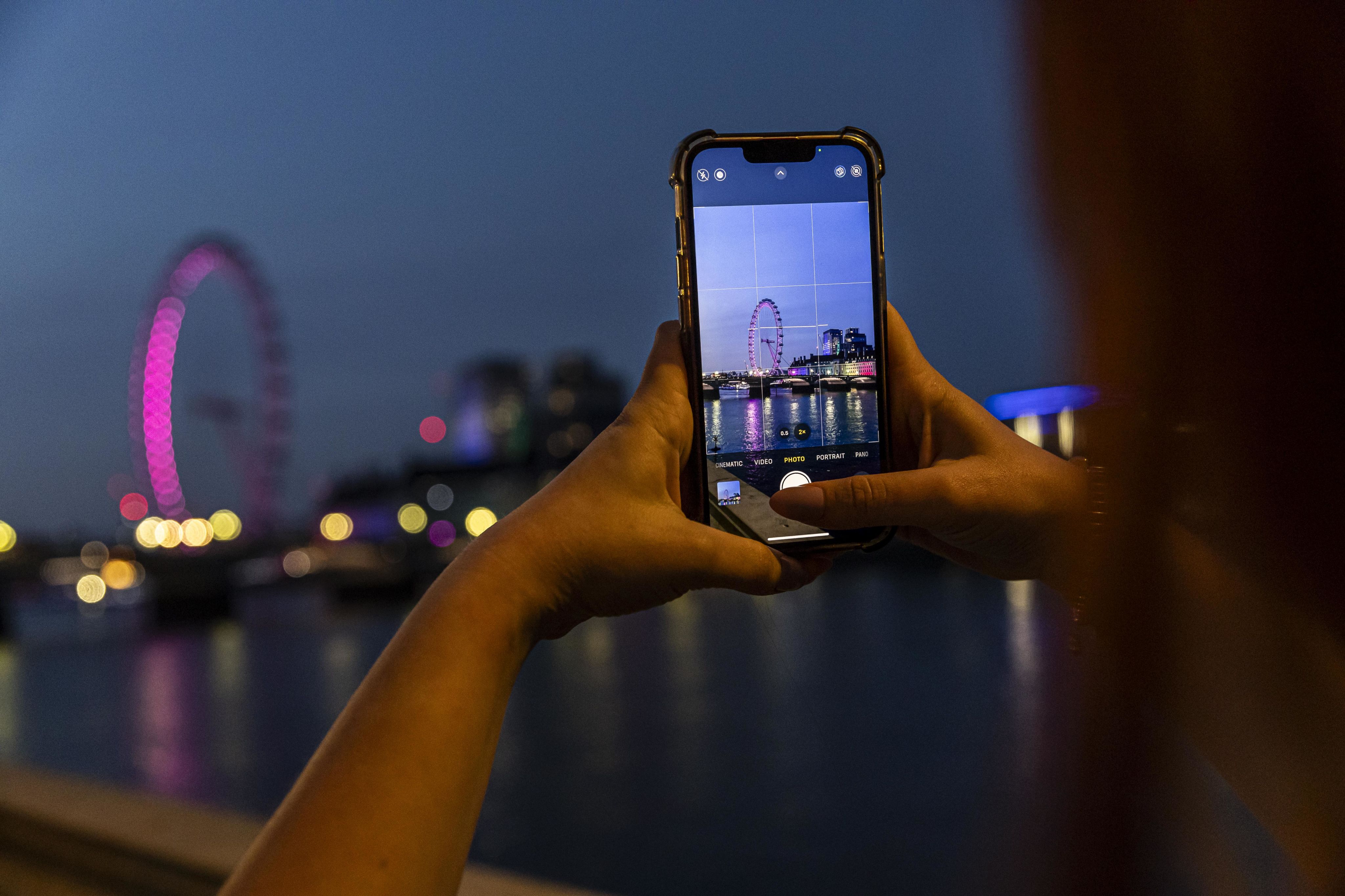 Someone takes a photo of the London eye at night on their phone