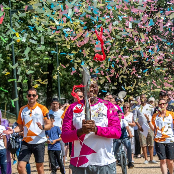 Brian Kokoruwe runs with the Baton through a crowd as confetti rains from above