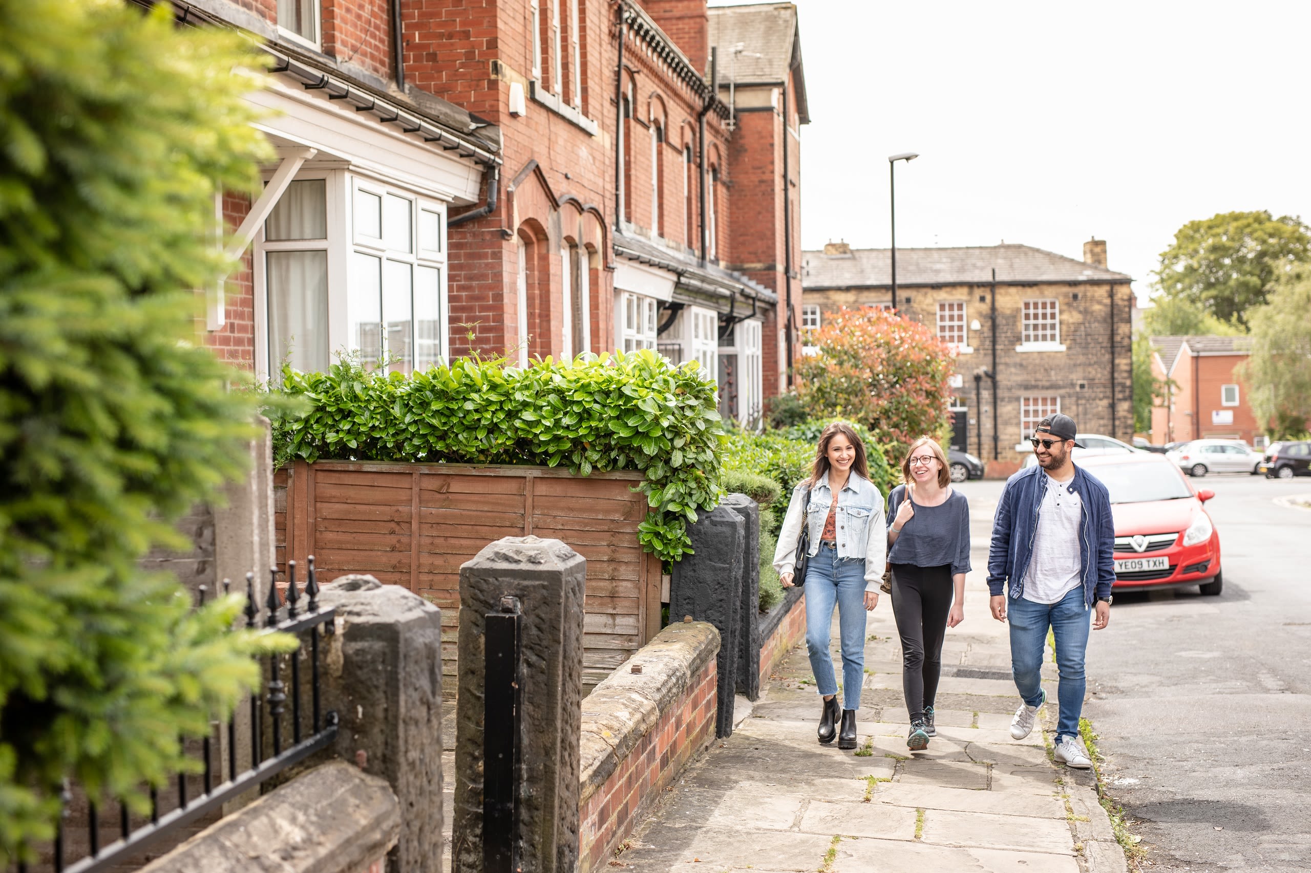 Three people walking through a residential street on a sunny day