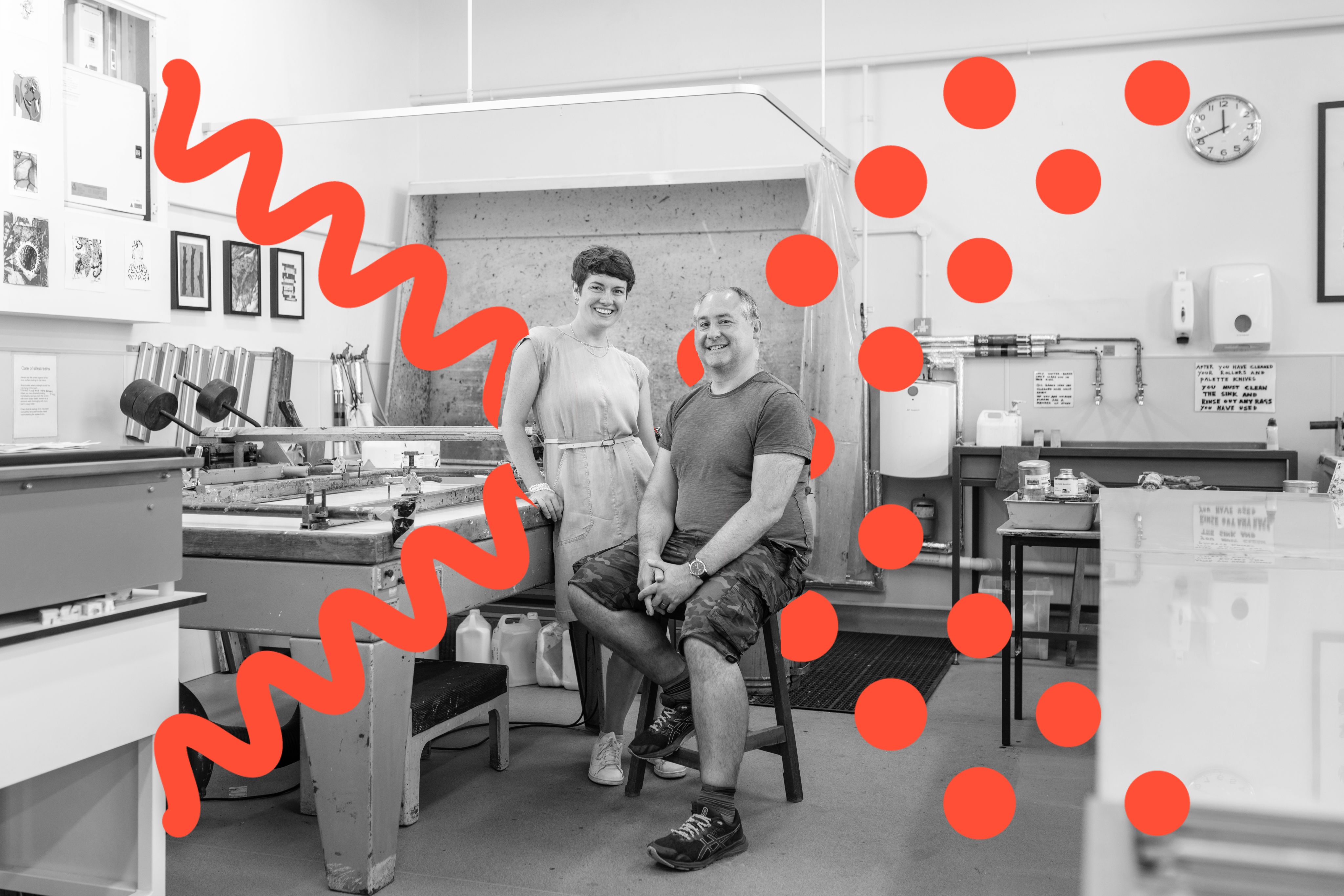 Portrait of Caitlin and Paul in a workshop. There are workbenches with equipment around them.