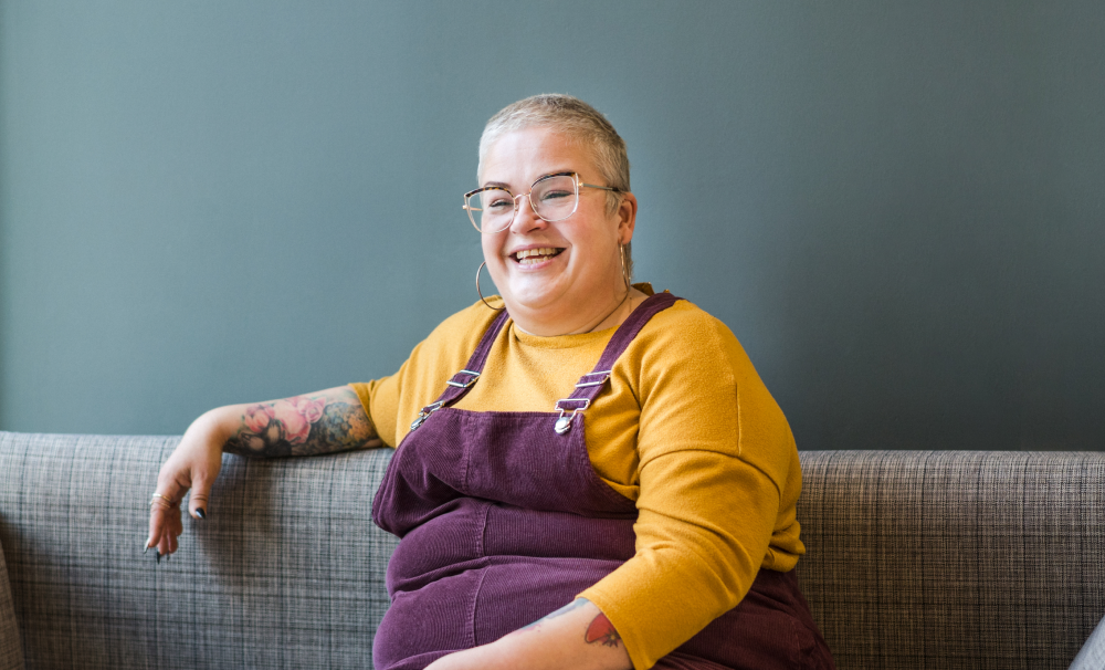 Sadie Augier sits on a sofa, laughing