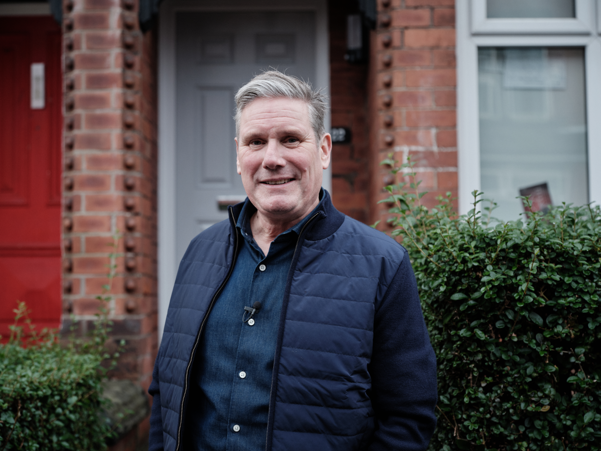 Keir Starmer stood in front of a Victorian, red-brick student house