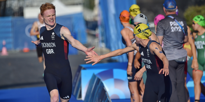 Two triathletes tag hands at the changeover station in the relay race
