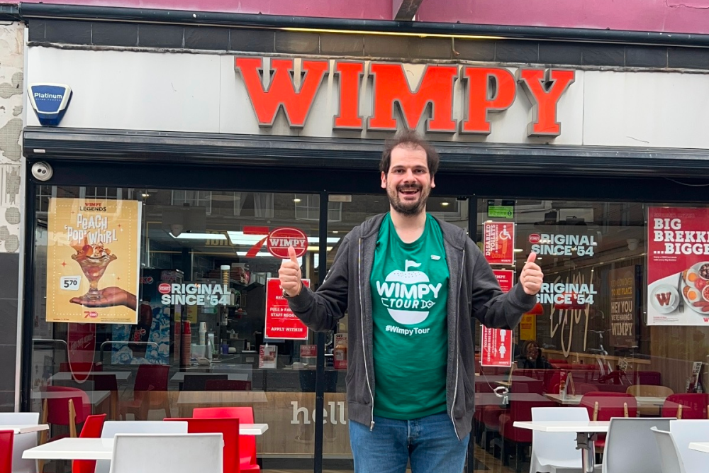 Man gives a thumbs up outside a Wimpy restaurant