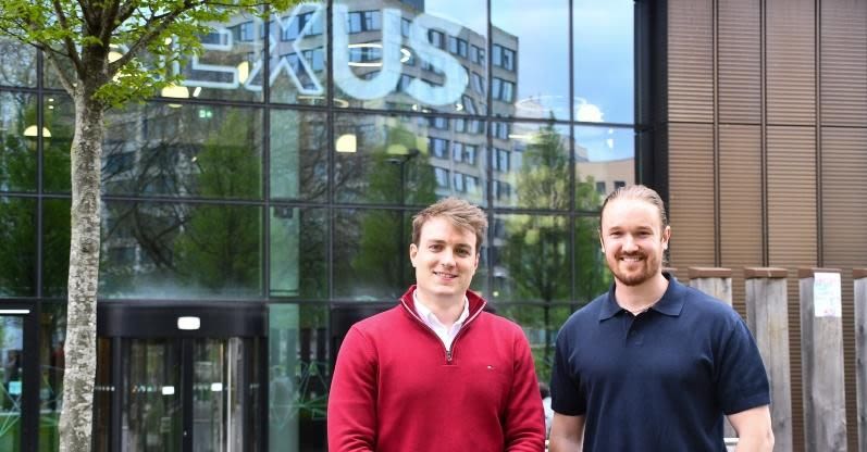 Two men stand side by side outside a building