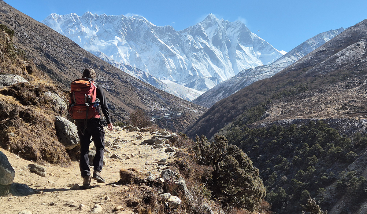 A hiker walks towards high mountains in the distance