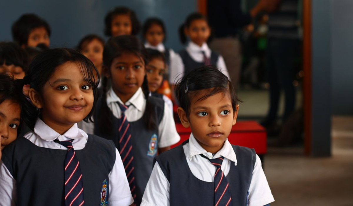 A group of school children smile in class