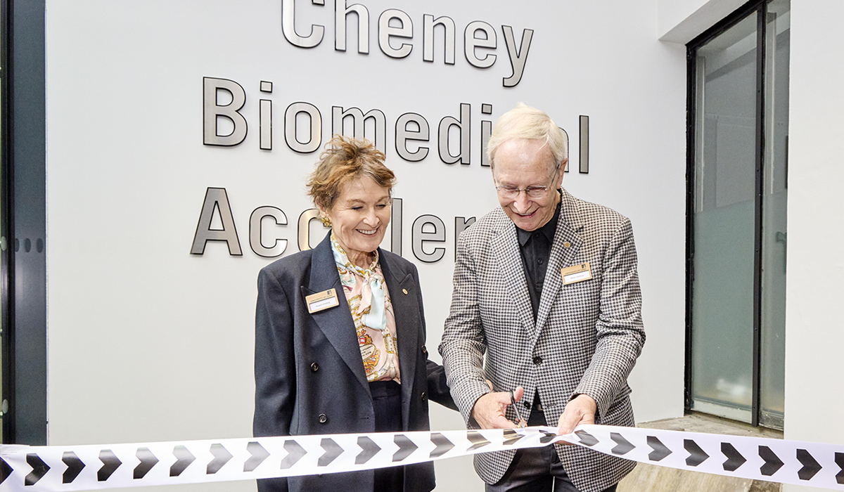 Two individuals cutting the ribbon to open a building