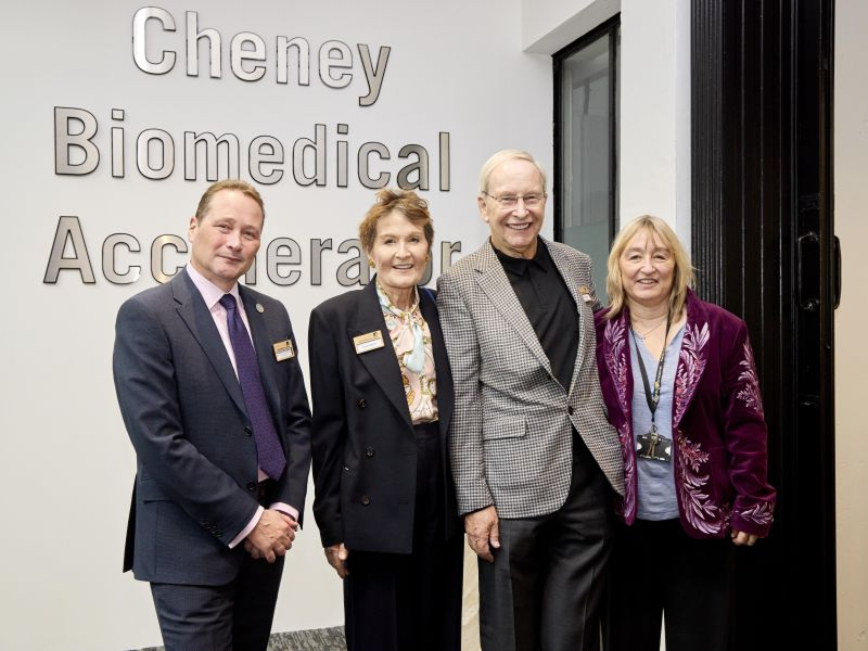 Four individuals stand at the entrance to the new building