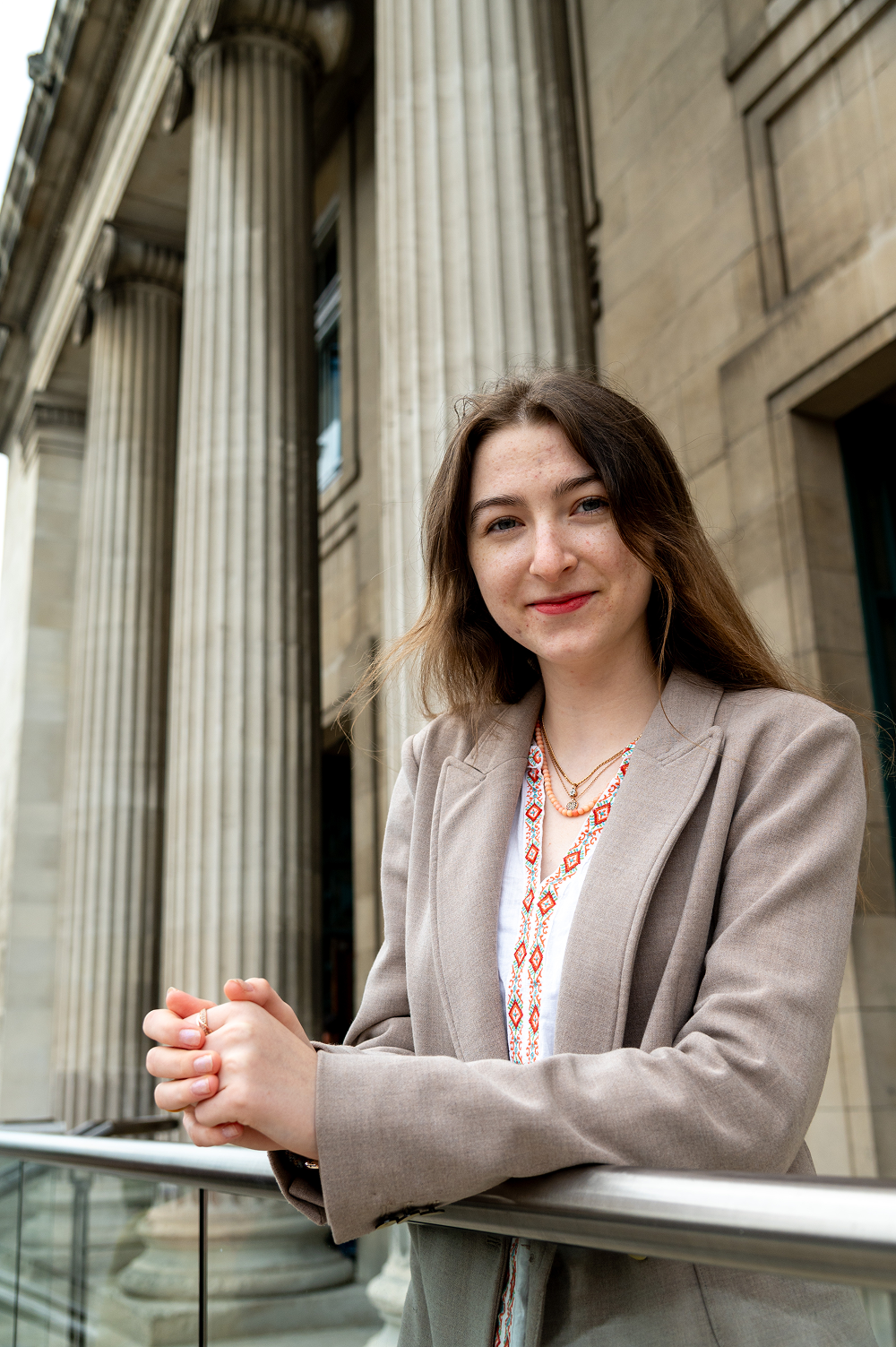 An individual leans against a railing outside the Parkinson Building at the University of Leeds