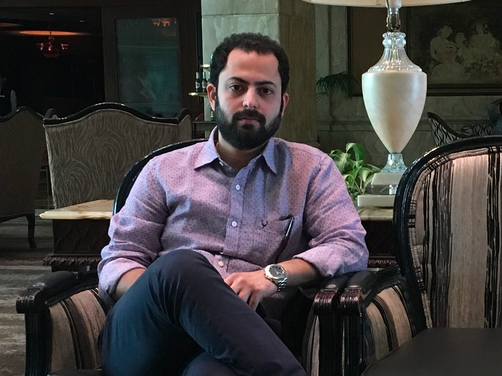 Profile image of Sharique Khan sat in an office with his legs crossed