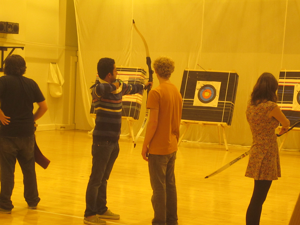 A man with a bow and arrow pointed at a target