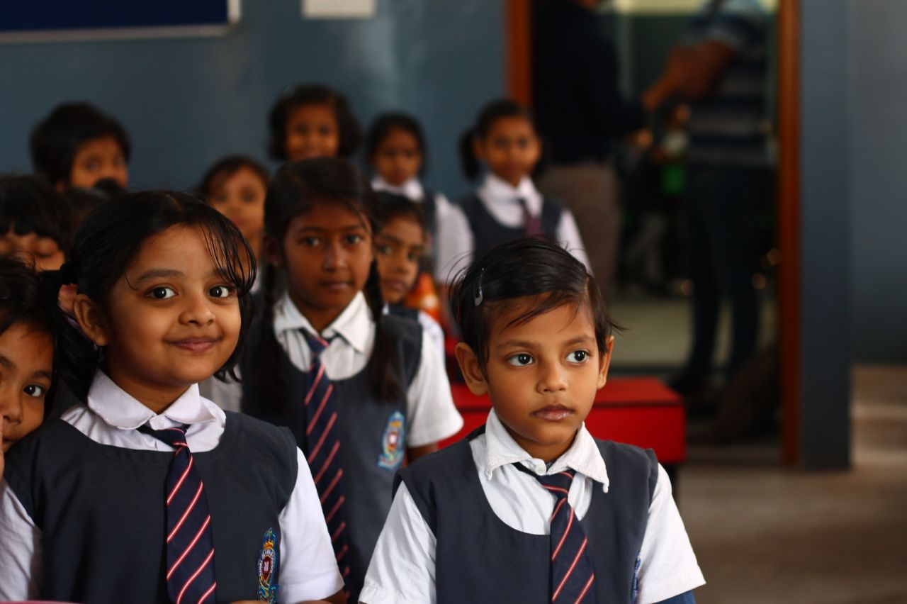 A group of school children stand in a classroom