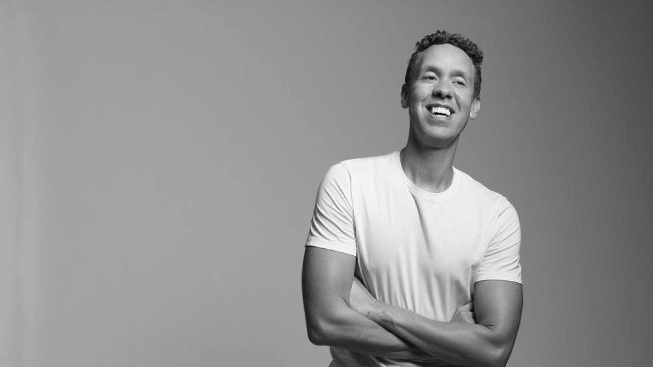 Leon Gray profile image in grayscale, smiling with his arms folded