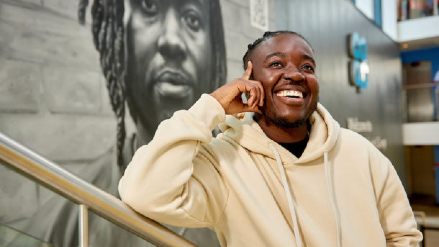 Melz smiles in front of a mural in the Leeds University Union