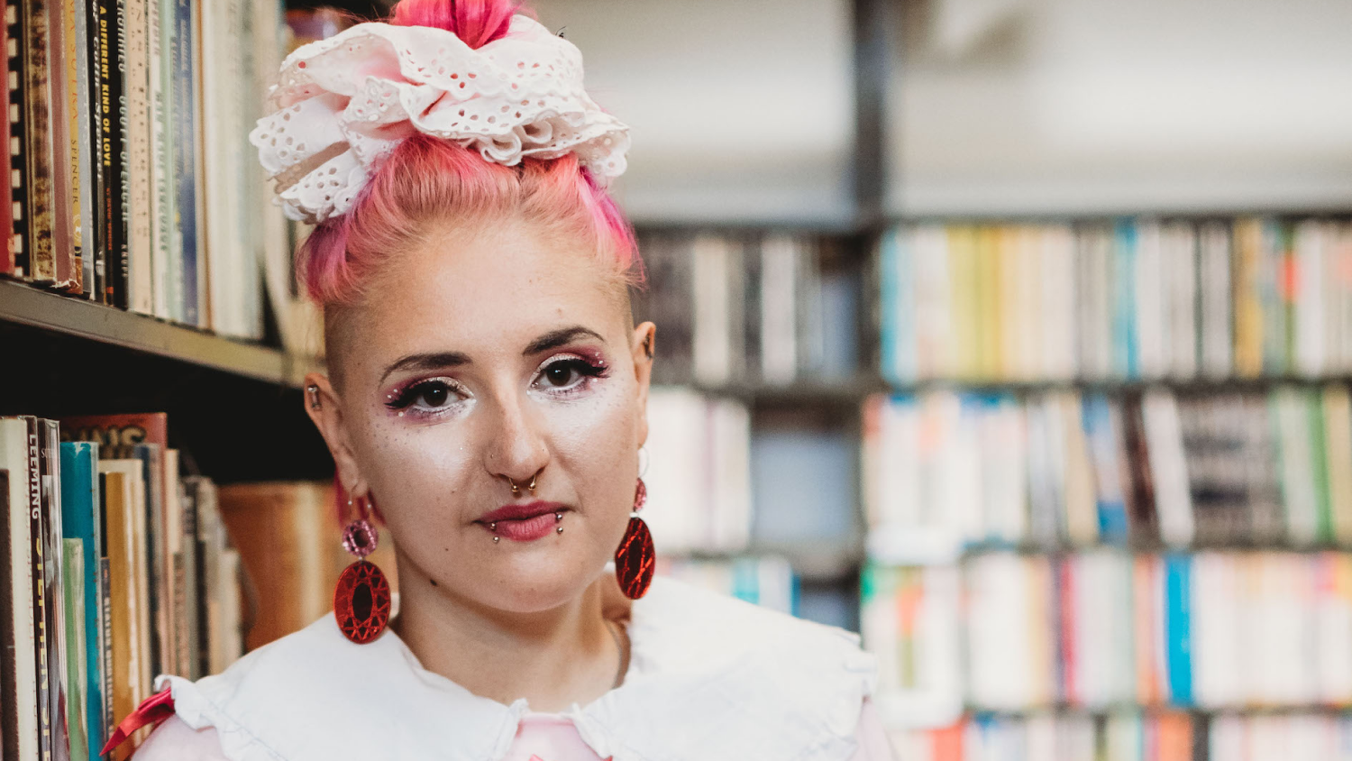 Sarah-Joy Ford profile image, stood next to shelves in a library