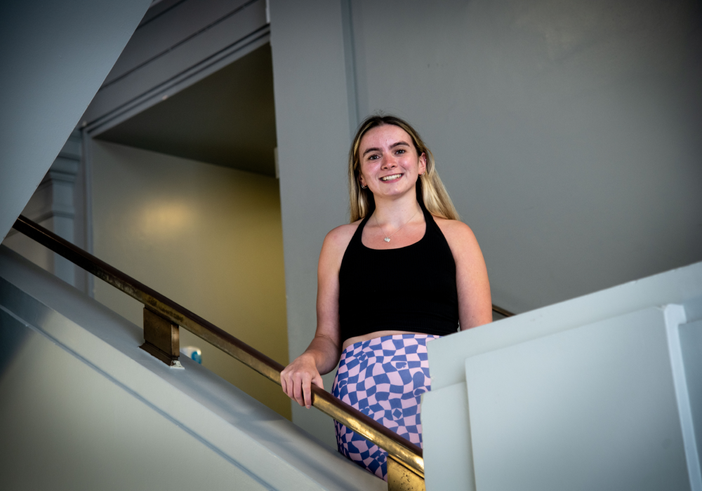 Claire stands upon a staircase looking down at the camera