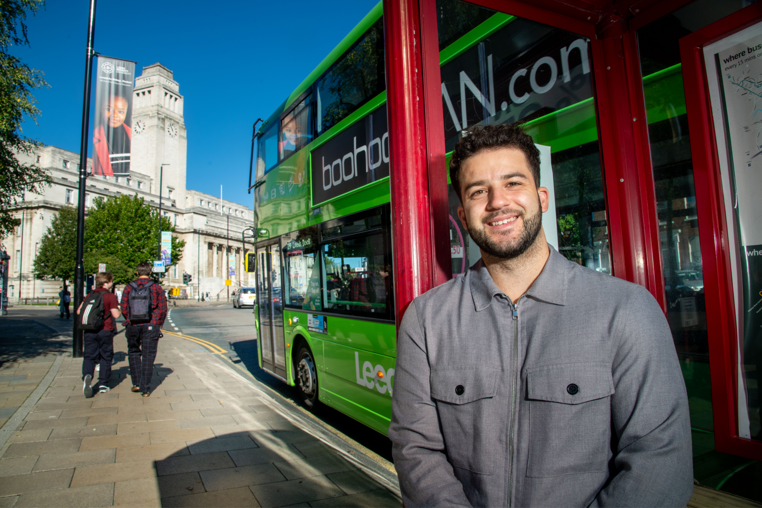 Cameron stands before a bus as it drives past the Parkinson Building