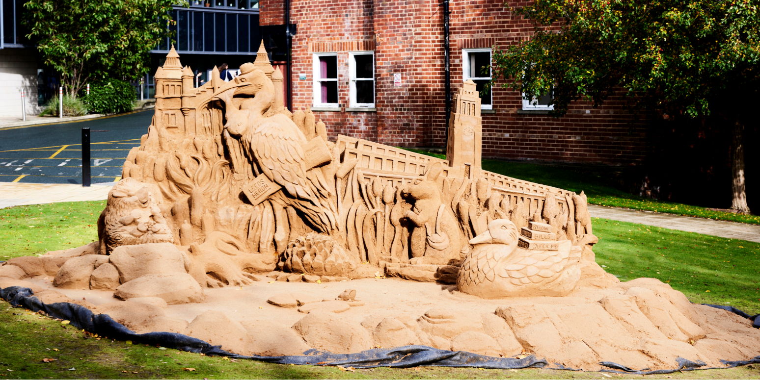 A sand sculpture of Leeds campus is pictured upon the green outside the Edward Boyle Library