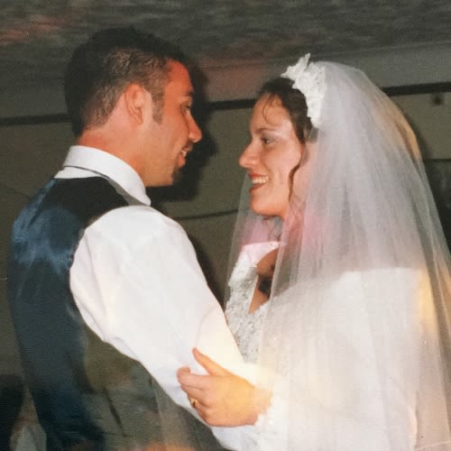A couple on their wedding day. The man in a suit and woman in a wedding dress are looking at each other and dancing