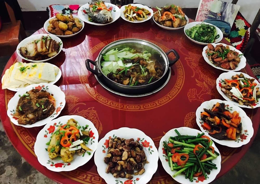 A banquet of many dishes of food laid out on a decorative circular table.