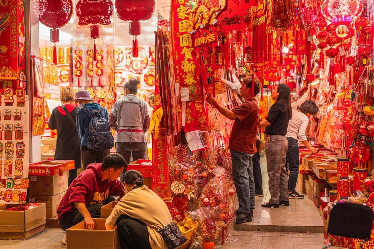 People browsing inside a shop that is filled to the brim with red and gold coloured decorations for Lunar New Year