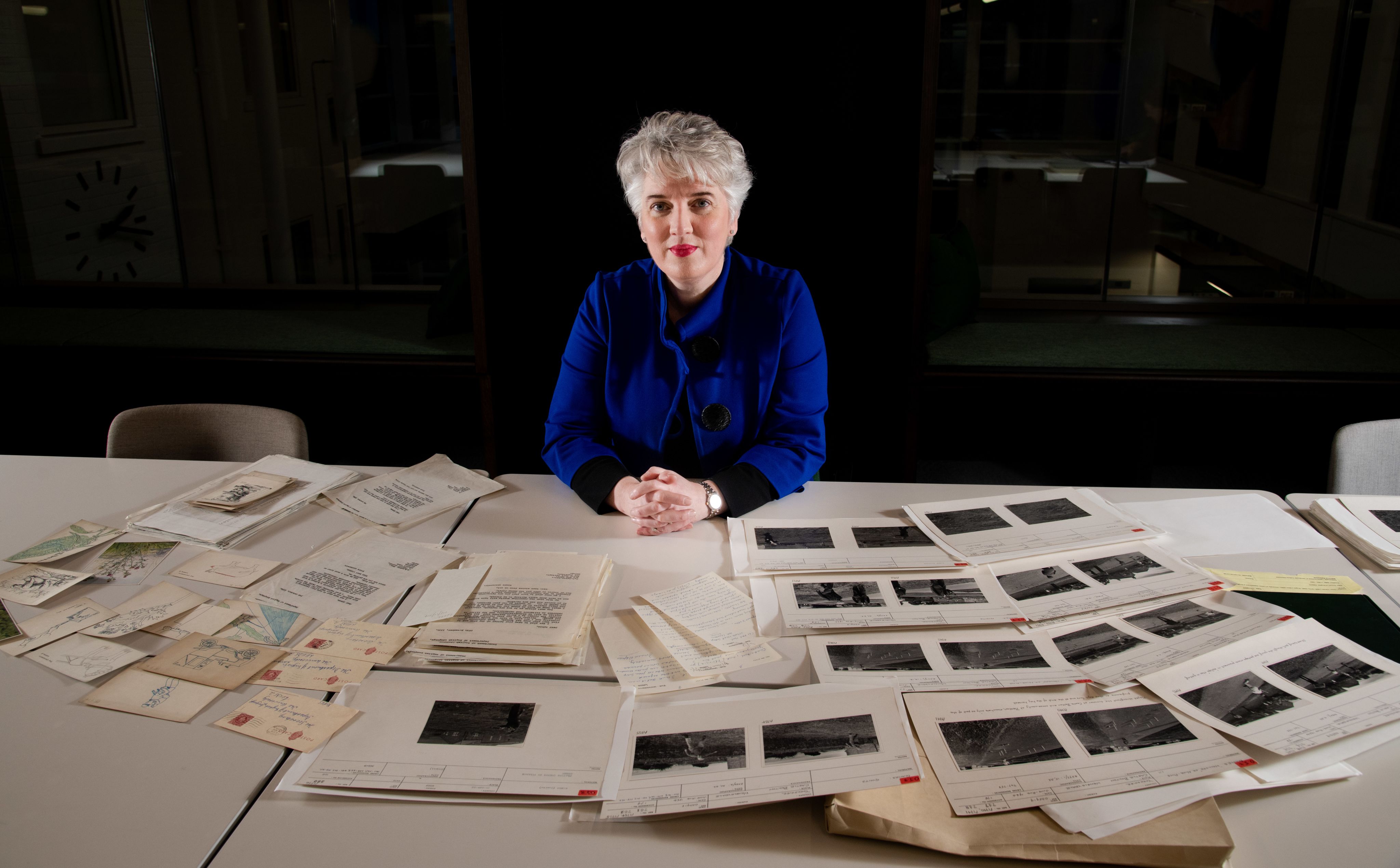 Woman surrounded by old papers and photographs.