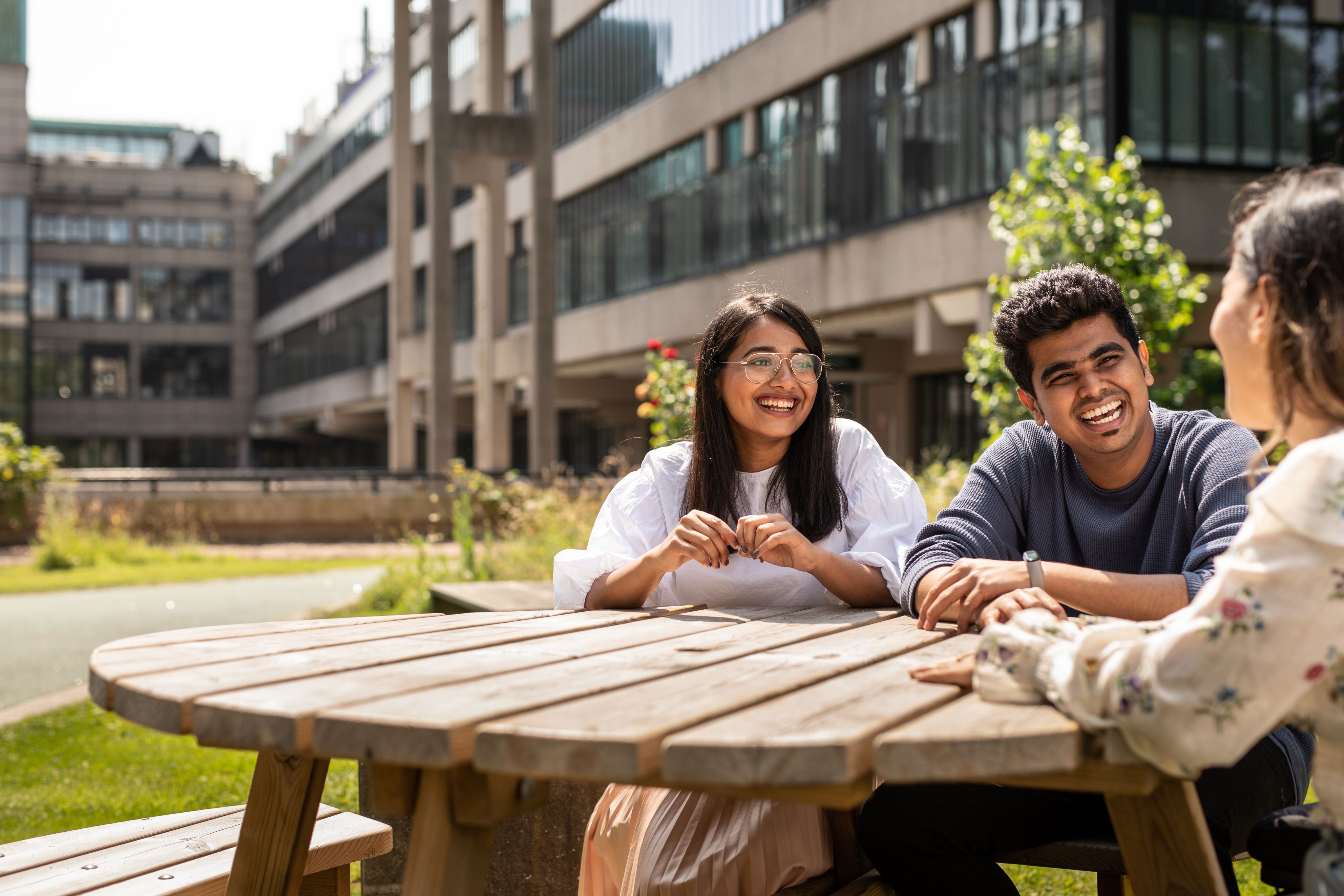 Three students sat at a table on campus.